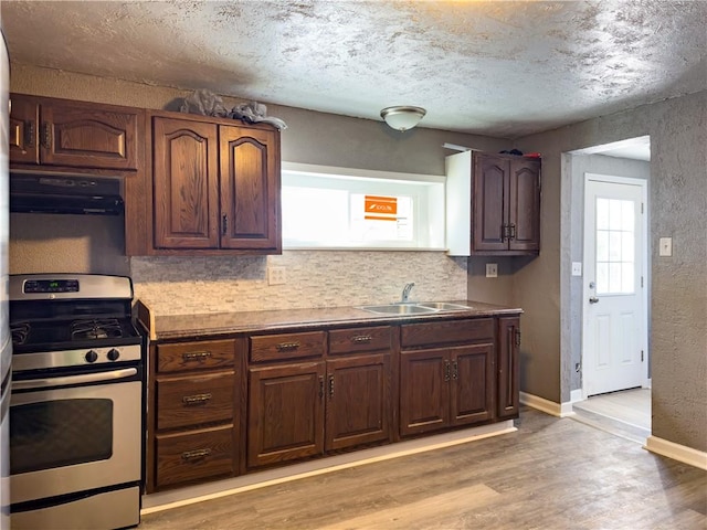 kitchen with range hood, sink, light wood-type flooring, gas stove, and a textured ceiling