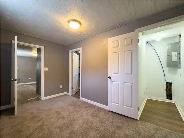 unfurnished bedroom featuring electric panel, a textured ceiling, and dark colored carpet