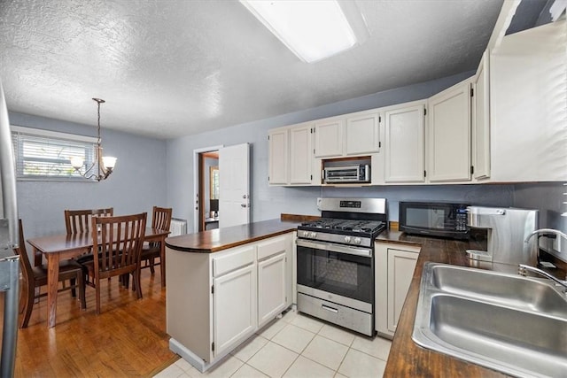 kitchen featuring white cabinets, sink, stainless steel appliances, and hanging light fixtures