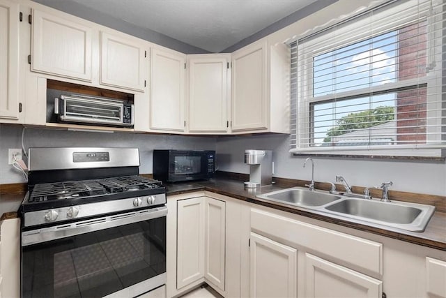 kitchen featuring white cabinets, gas range, and sink