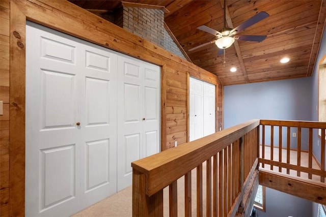 corridor featuring carpet, lofted ceiling, wooden ceiling, and wood walls