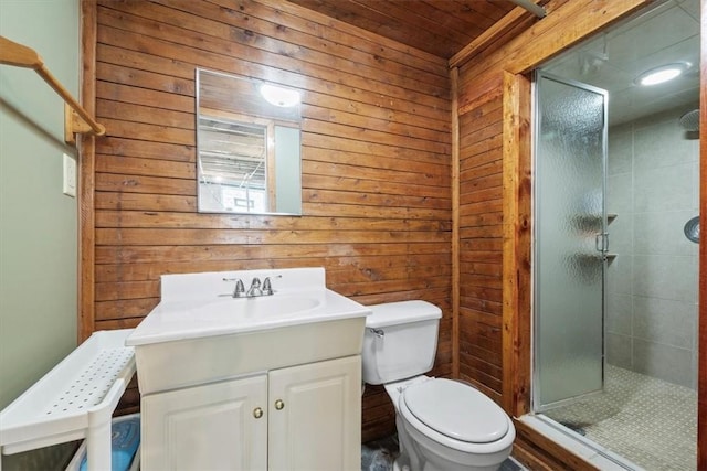 bathroom featuring vanity, toilet, a shower with door, and wood walls