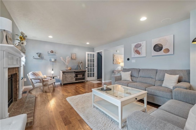 living room with hardwood / wood-style flooring and a brick fireplace