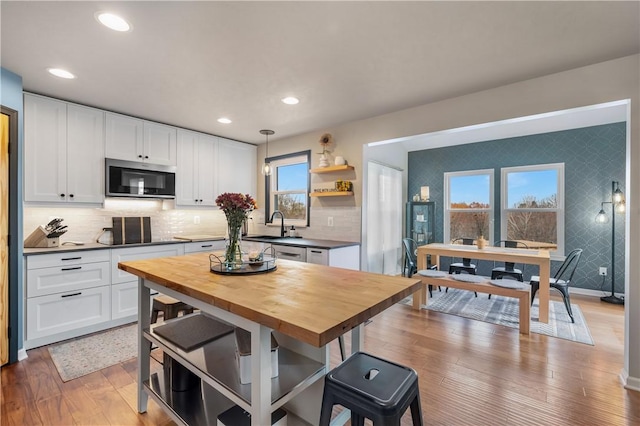 kitchen featuring sink, wooden counters, hardwood / wood-style floors, decorative light fixtures, and white cabinets