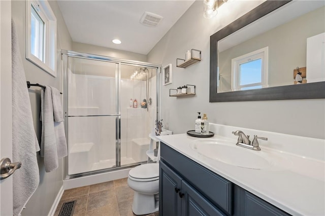 bathroom featuring vanity, toilet, a shower with door, and a wealth of natural light