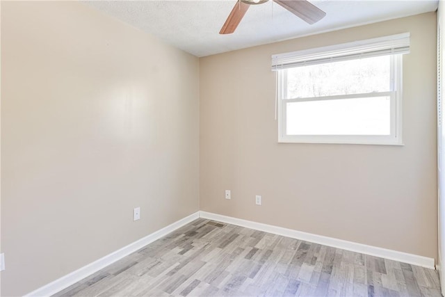 spare room featuring ceiling fan, light wood-type flooring, and a textured ceiling