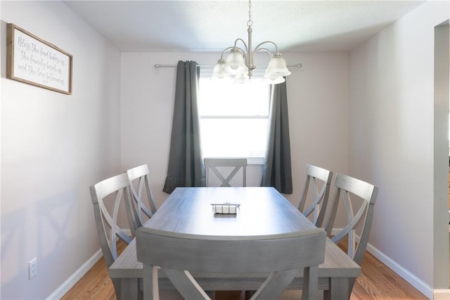 dining area with light hardwood / wood-style flooring and an inviting chandelier