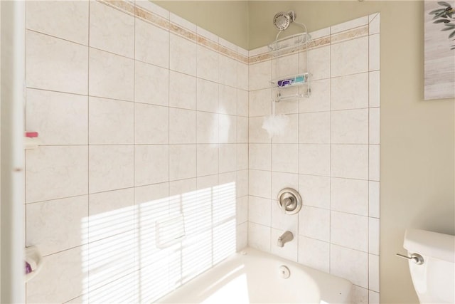 bathroom with toilet and tiled shower / bath