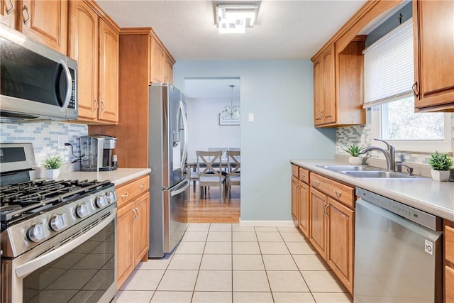 kitchen with appliances with stainless steel finishes, tasteful backsplash, light tile patterned floors, and sink