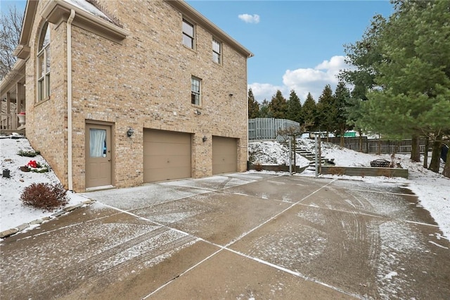 view of snowy exterior featuring a garage