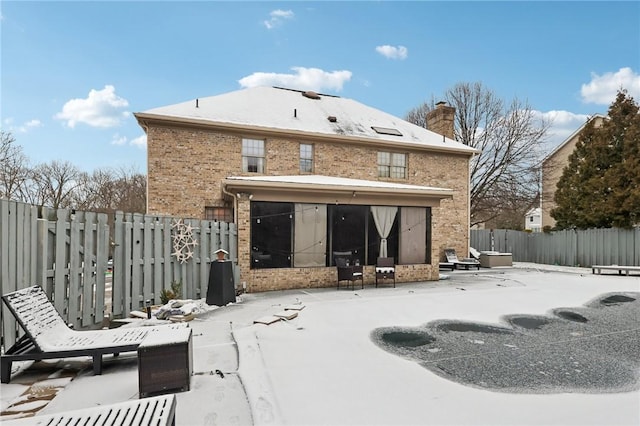 snow covered back of property featuring a sunroom