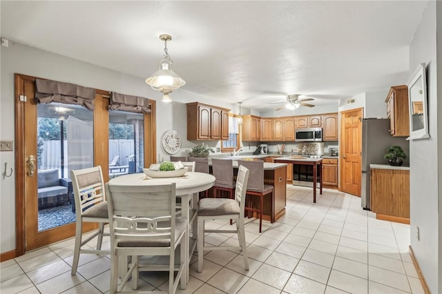 tiled dining space featuring ceiling fan, sink, and a wealth of natural light