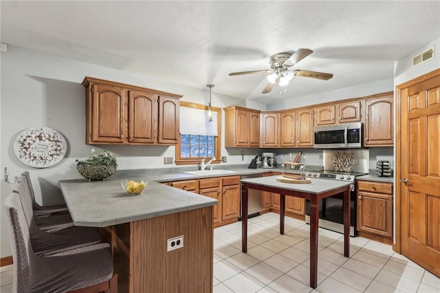 kitchen with sink, ceiling fan, light tile patterned floors, decorative light fixtures, and stainless steel appliances