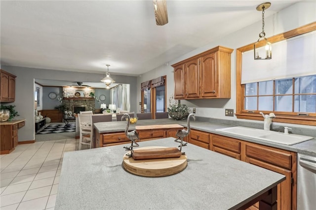 kitchen featuring sink, a brick fireplace, stainless steel dishwasher, decorative light fixtures, and a kitchen island