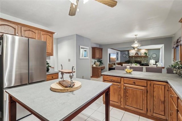 kitchen with ceiling fan, light tile patterned floors, decorative light fixtures, a fireplace, and stainless steel refrigerator