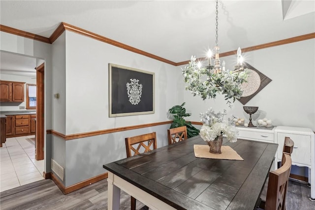 dining room featuring light hardwood / wood-style floors, crown molding, and a notable chandelier