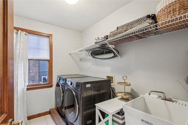 washroom with light tile patterned flooring, washer and dryer, and sink