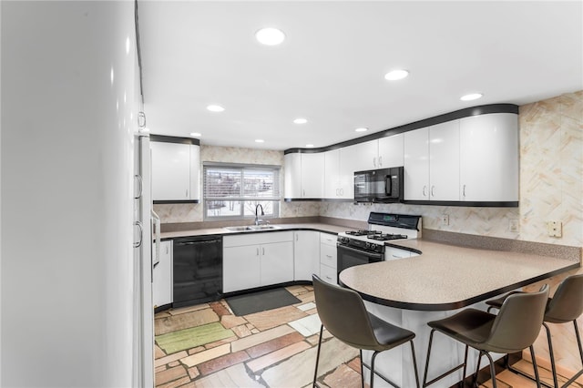 kitchen featuring white cabinetry, sink, a kitchen breakfast bar, decorative backsplash, and black appliances