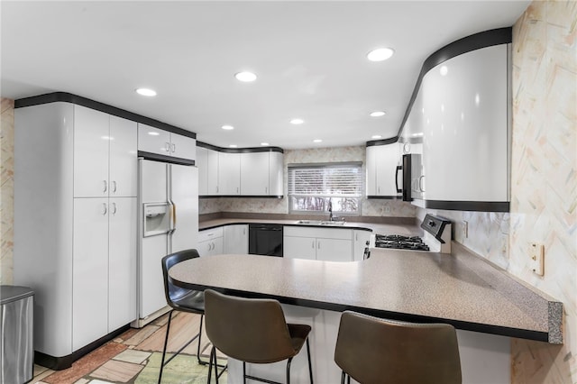 kitchen with white cabinetry, white refrigerator with ice dispenser, kitchen peninsula, a kitchen bar, and range