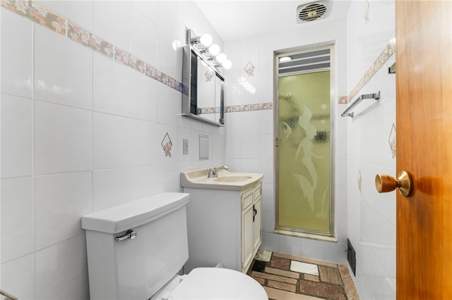 bathroom with vanity, toilet, tile walls, and a shower with shower door