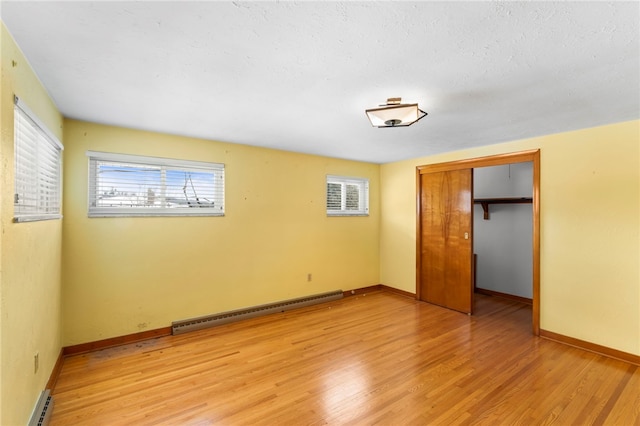 unfurnished bedroom with a closet, a baseboard radiator, and light hardwood / wood-style flooring