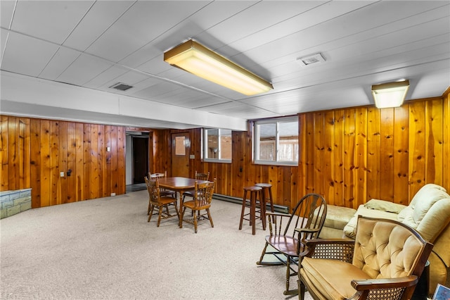 living area featuring wood walls, carpet floors, and a baseboard heating unit