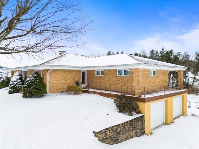 snow covered rear of property with a garage and a balcony