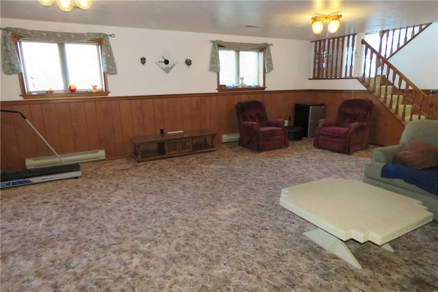 carpeted living room with a baseboard radiator, a wealth of natural light, and wood walls