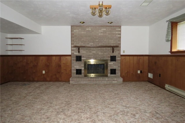 unfurnished living room featuring a textured ceiling, wood walls, a fireplace, and a baseboard heating unit