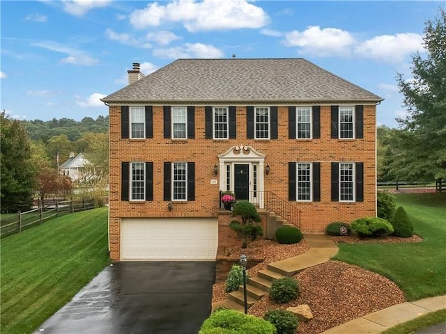 colonial-style house with a front yard and a garage