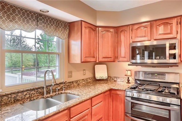 kitchen featuring light stone counters, sink, and appliances with stainless steel finishes