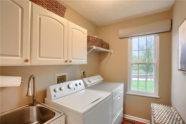 clothes washing area with washer and clothes dryer, cabinets, and sink