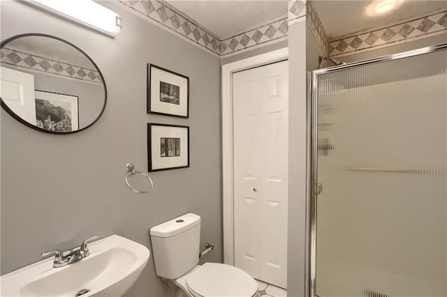 bathroom with toilet, a shower with door, and sink