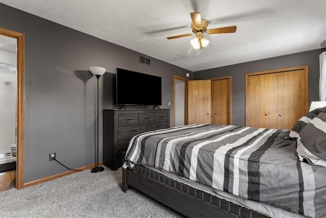 bedroom with two closets, light colored carpet, and ceiling fan