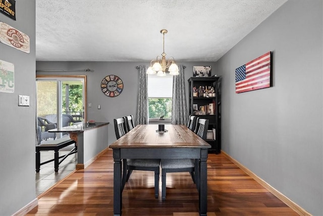 dining space featuring a chandelier, a textured ceiling, and hardwood / wood-style flooring