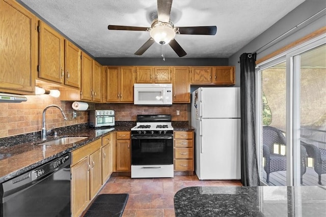 kitchen with backsplash, dark stone counters, white appliances, ceiling fan, and sink