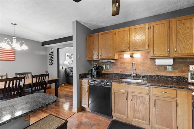 kitchen featuring sink, decorative light fixtures, a notable chandelier, dark stone countertops, and black dishwasher