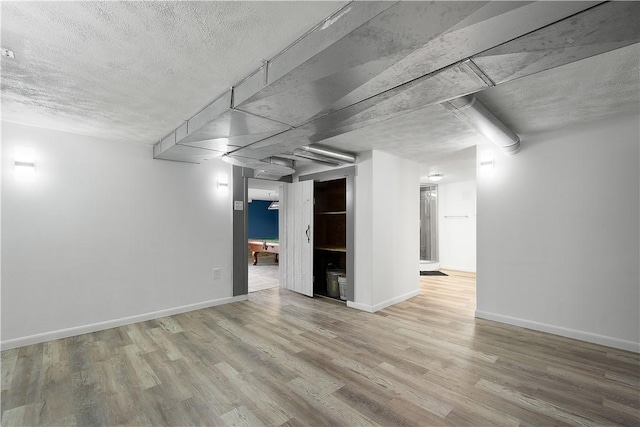 basement featuring a textured ceiling and hardwood / wood-style flooring