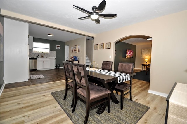 dining room featuring ceiling fan, sink, and light hardwood / wood-style flooring