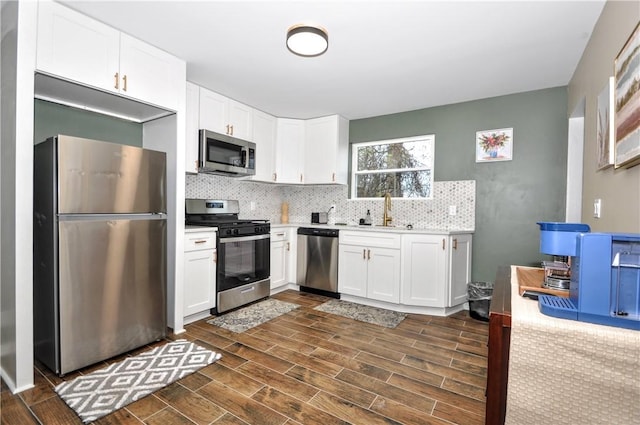 kitchen with backsplash, sink, white cabinetry, and stainless steel appliances