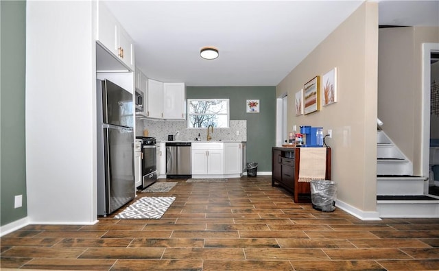 kitchen with backsplash, white cabinetry, sink, and stainless steel appliances