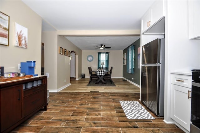 kitchen featuring ceiling fan, black fridge, and white cabinetry