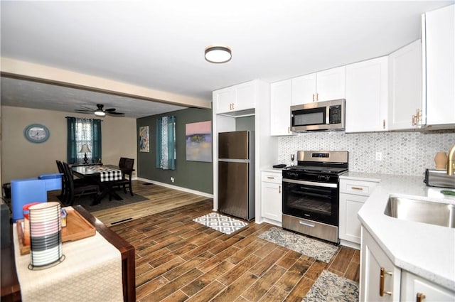 kitchen with backsplash, white cabinetry, ceiling fan, and stainless steel appliances