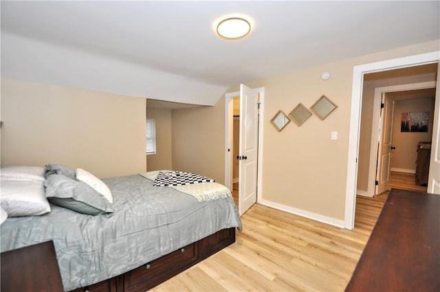 bedroom with vaulted ceiling and light hardwood / wood-style flooring