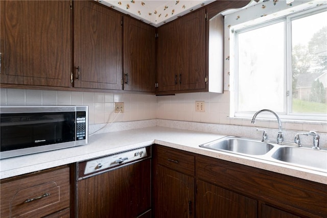 kitchen with dishwasher, dark brown cabinets, backsplash, and sink