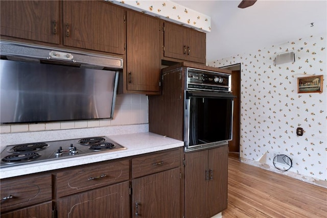 kitchen with tasteful backsplash, oven, light hardwood / wood-style floors, and gas cooktop