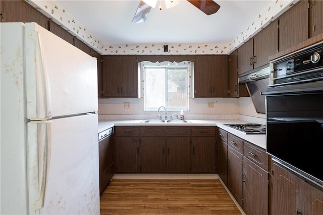 kitchen with black appliances, dark brown cabinets, sink, and light hardwood / wood-style flooring