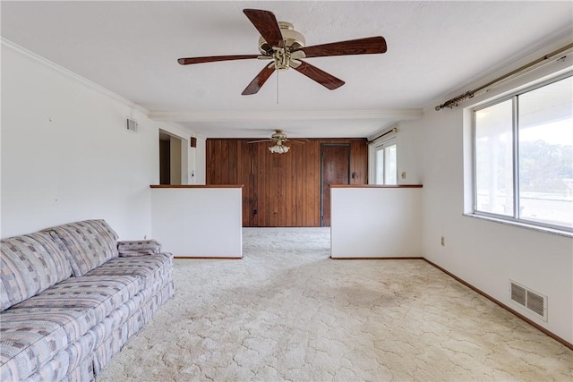 unfurnished living room featuring ceiling fan, wood walls, and light carpet