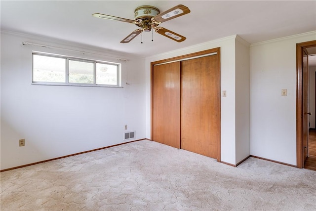 unfurnished bedroom featuring light colored carpet, a closet, ornamental molding, and ceiling fan