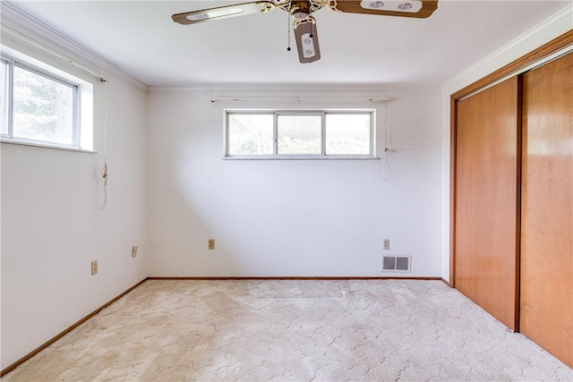 unfurnished bedroom with a closet, light colored carpet, ceiling fan, and ornamental molding